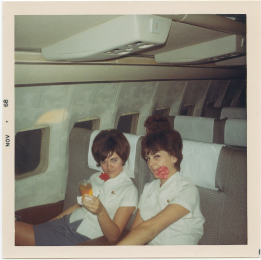 1968 November Susanne Malm & colleague pose between flights in the first class cabin of a Pan Am  Boeing707 with flowers left behind by customers from the last flight.  For many years Pan Am placed fresh flowers on First Class meal trasys.